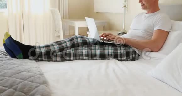 男人在家里卧室里用笔记本电脑视频的预览图
