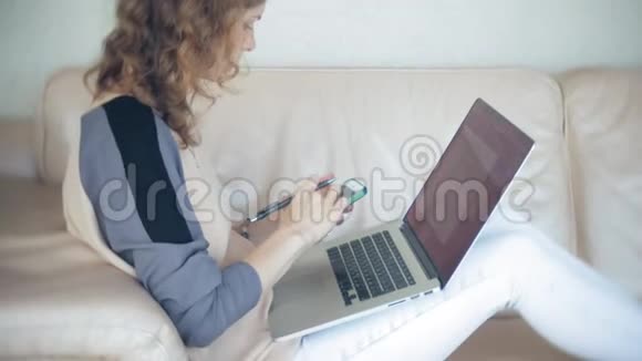 年轻漂亮的女商人坐在沙发上桌上放着平板电脑视频的预览图