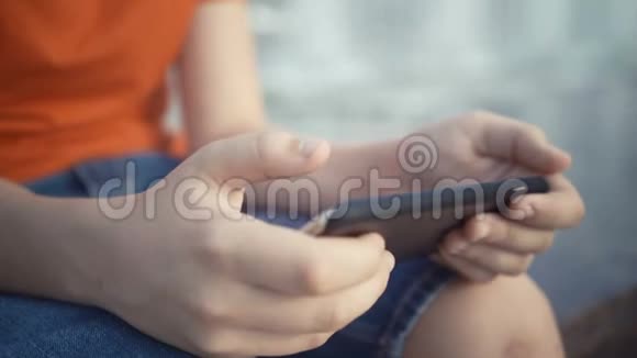 小男孩在他的智能手机上玩电子游戏视频的预览图