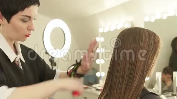 理发师在美发沙龙女性理发前梳理长发在美容院贴紧女性发型视频的预览图