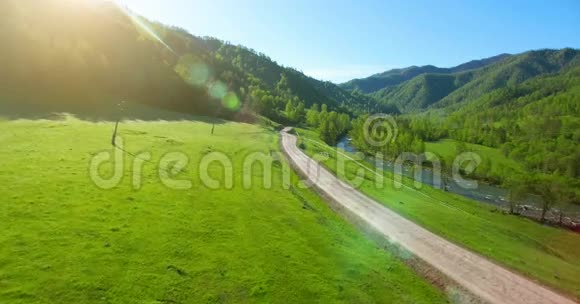 空中UHD4K视野阳光明媚的夏日清晨低空飞越高山乡村土路和草地视频的预览图