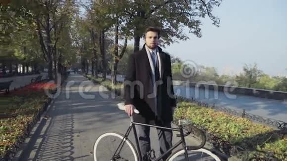 年轻的商人骑着自行车站在城市小巷里视频的预览图