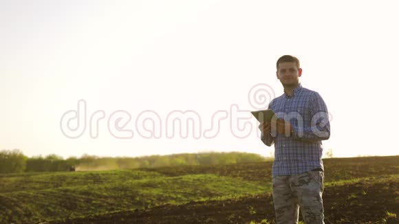 一位年轻漂亮的农民学生在田里干活手里拿着拖拉机手里拿着里面的肖像视频的预览图