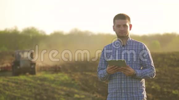 一位年轻漂亮的农民学生在田里工作拖拉机在平板上工作生活方式的肖像视频的预览图