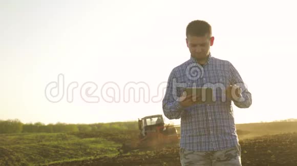 一位年轻漂亮的农民学生在田里干活手里拿着拖拉机手里拿着里面的肖像视频的预览图