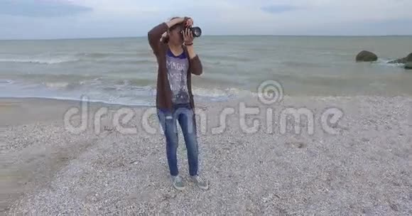 女孩摄影师在海滩上拍摄视频的预览图