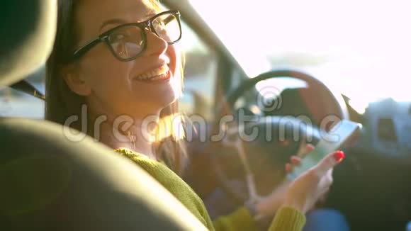 戴眼镜的女人在车里用智能手机视频的预览图