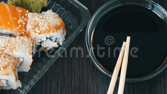 时尚的寿司放在黑色的木制背景上旁边是酱油和中国竹签各种寿司卷视频的预览图