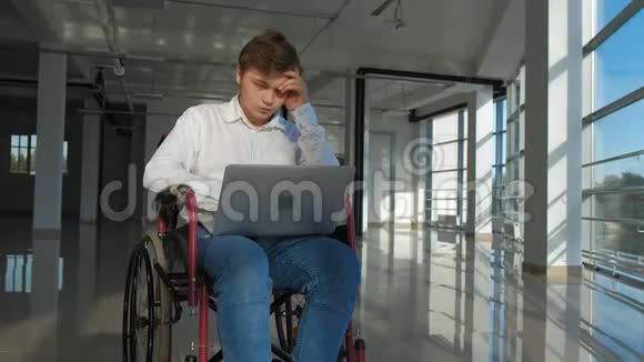 一个坐轮椅的残疾人商人在窗户上拿着笔记本电脑视频的预览图