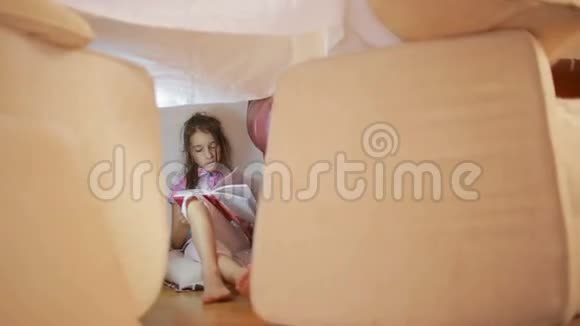 一个小女孩坐在一个临时的枕头屋和一个毯子屋里视频的预览图