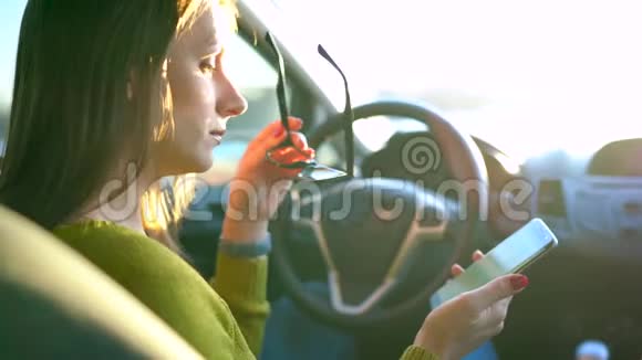 戴眼镜的女人在车里用智能手机视频的预览图