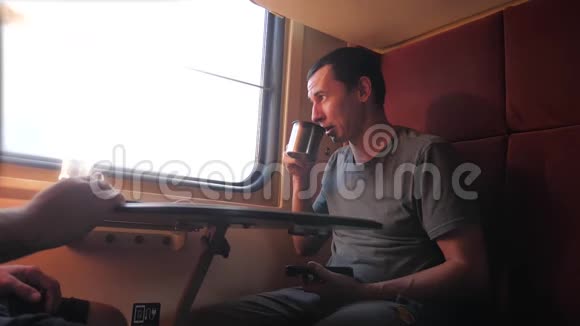男人坐在火车车厢上手里拿着智能手机铁路喝着咖啡和茶慢动作视频男人视频的预览图