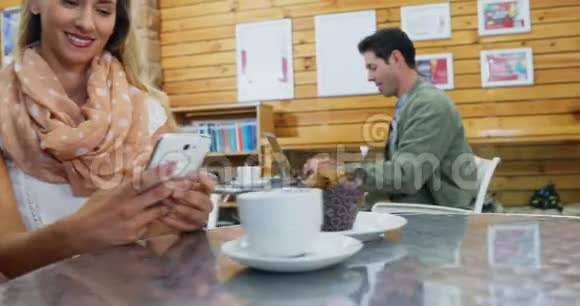 妇女在喝咖啡时使用手机视频的预览图