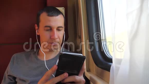 男子听着火车车厢车厢车厢车厢上的音乐旅行慢动作视频有智能手机的男人视频的预览图