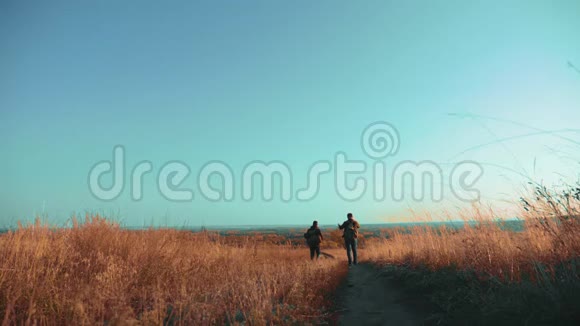 两个徒步旅行的人带着背包的生活方式沿着爬山的小路走着慢动作视频的预览图
