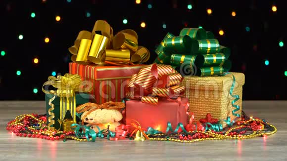 漂亮的圣诞礼品盒和装饰在木地板上五颜六色的闪光花环在黑色的背景上无缝视频的预览图