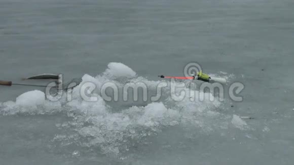 冬天河上的钓鱼竿在洞口附近的冰上视频的预览图