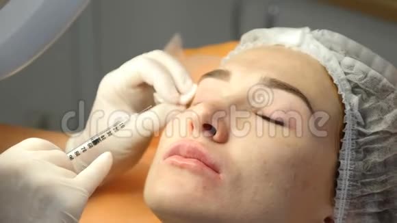 美容诊所美容师用手套在女性皮肤上进行面部老化注射一个女人得到美丽的脸视频的预览图