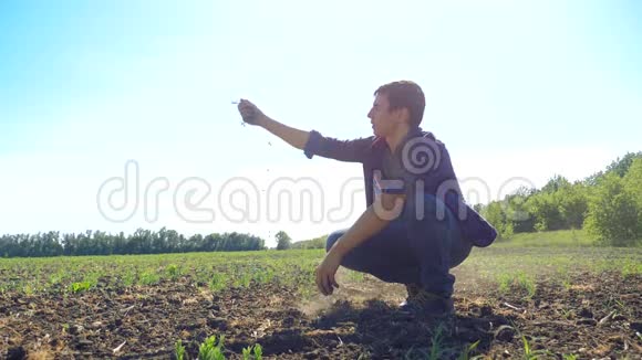 男人农民手里握着新鲜的土壤慢动作视频大地的泥土使大地保持着春天的象征视频的预览图