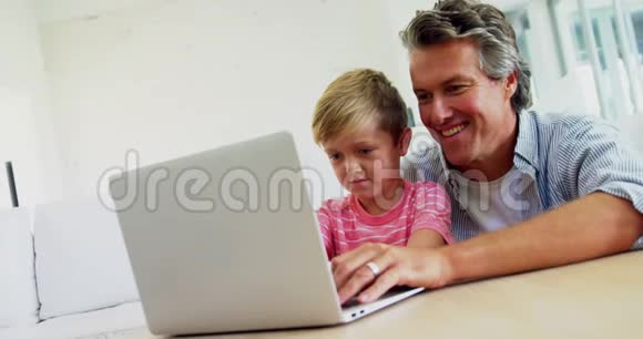 父亲和儿子在4k客厅用笔记本电脑视频的预览图