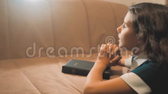 小女孩在夜里祈祷小女孩用手祈祷小女孩圣经在生活方式中祈祷圣经视频的预览图
