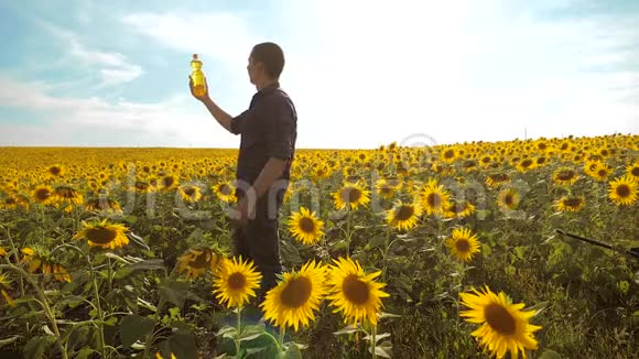 日落时分农夫手捧生活方式的葵花籽油农民农业塑料瓶视频的预览图