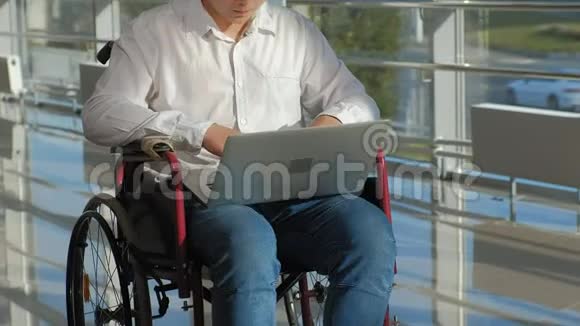 一个坐轮椅的残疾人商人在窗户上拿着笔记本电脑视频的预览图