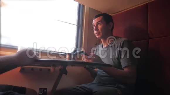 男人坐在火车车厢上手里拿着智能手机铁路喝着咖啡和茶慢动作视频男人视频的预览图
