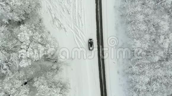 雪林中的冬季乡村道路无人驾驶飞机鸟瞰视频的预览图