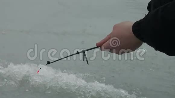 冬天河上的钓鱼竿在洞口附近的冰上视频的预览图