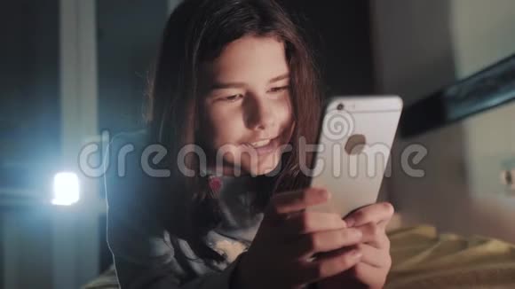 青少年生活方式女孩网上购物在她的智能手机在床上过夜一个小少女写的视频的预览图