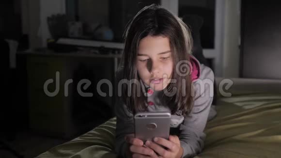 十几岁的女孩网上购物在床上看智能手机一个少女写生活方式视频的预览图