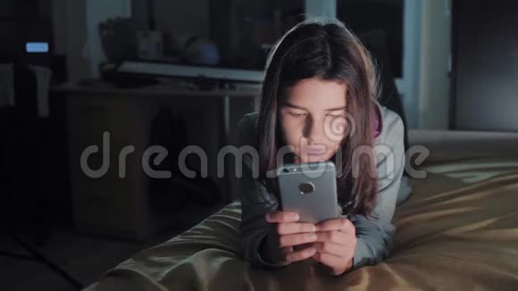 十几岁的女孩网上购物在她的智能手机上在床上生活方式在夜间一个小少女写的视频的预览图