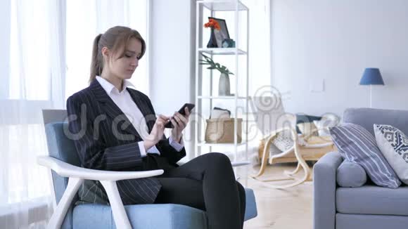 妇女使用智能手机在工作中在线浏览视频的预览图