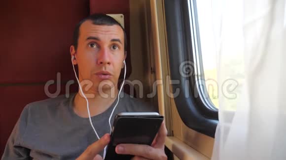 男子听着火车车厢车厢车厢车厢上的音乐旅行慢动作视频有智能手机的男人视频的预览图
