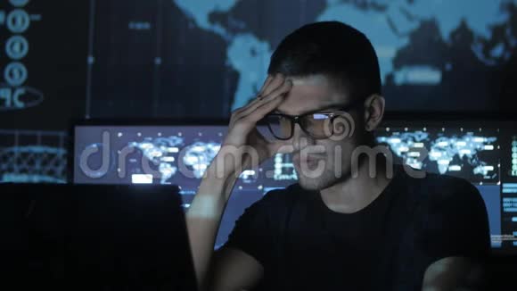 一位年轻的程序员在数据中心的一台电脑上工作的画像里面装满了显示屏视频的预览图