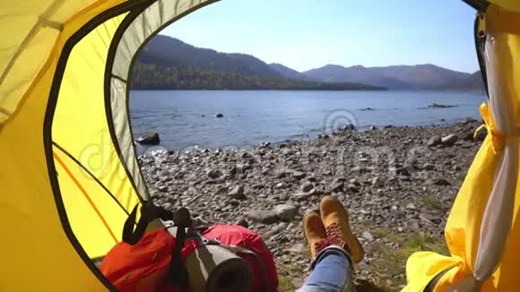 野营的女人躺在帐篷里穿着徒步旅行靴在度假时放松视频的预览图
