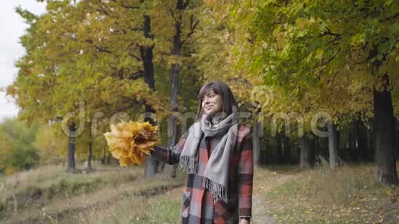黄色叶子的气味秋天的女孩在城市公园散步快乐可爱美丽的年轻女子画像视频的预览图