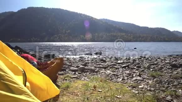 野营的女人躺在帐篷里穿着徒步旅行靴在度假时放松视频的预览图