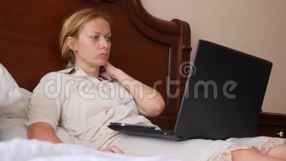 生活方式自由职业者那个女人在家里的床上工作在一台笔记本电脑后面4k慢动作视频的预览图