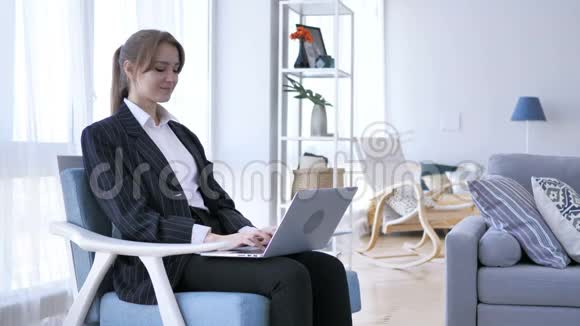 年轻女子在笔记本电脑上工作看着镜头视频的预览图