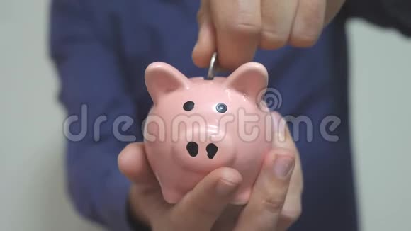 商人使储蓄把硬币的生活方式放在储蓄罐里猪银行的经营理念慢动作录像节约视频的预览图