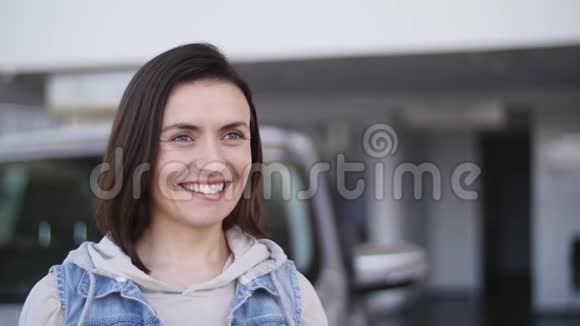 年轻女子拿着新车的钥匙对着镜头微笑视频的预览图