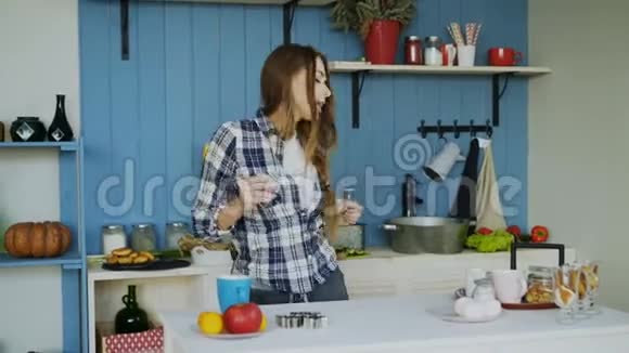 快乐的年轻有趣的女人在家里做饭时跳舞唱歌视频的预览图