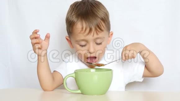 小孩坐在桌旁用勺子吃食物视频的预览图