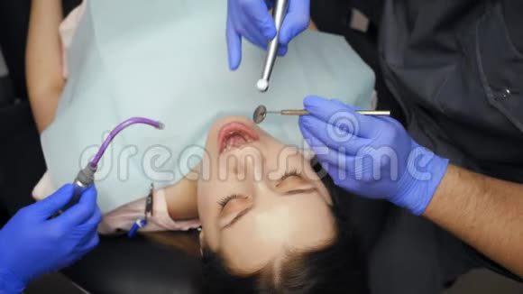 男牙科医生在诊所为年轻女性患者治疗牙齿视频的预览图