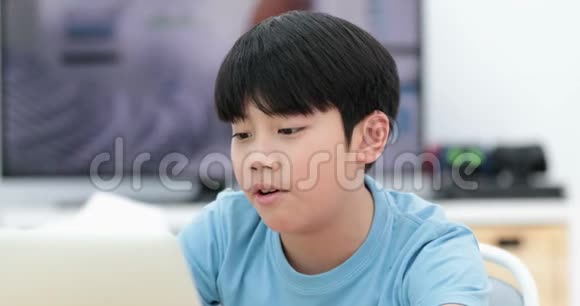 可爱的亚洲男孩在家里使用笔记本电脑视频的预览图