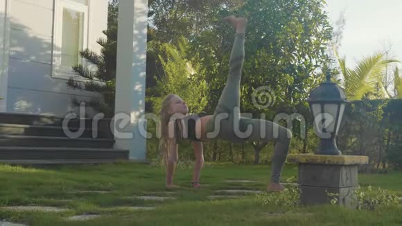 一个年轻女孩在自家后院做的体式瑜伽表演视频的预览图