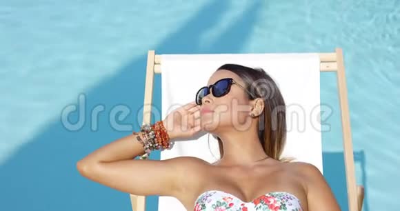 戴太阳镜的年轻女子在阳光下放松视频的预览图