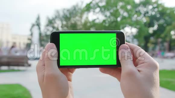双手拿着绿色屏幕的手机视频的预览图
